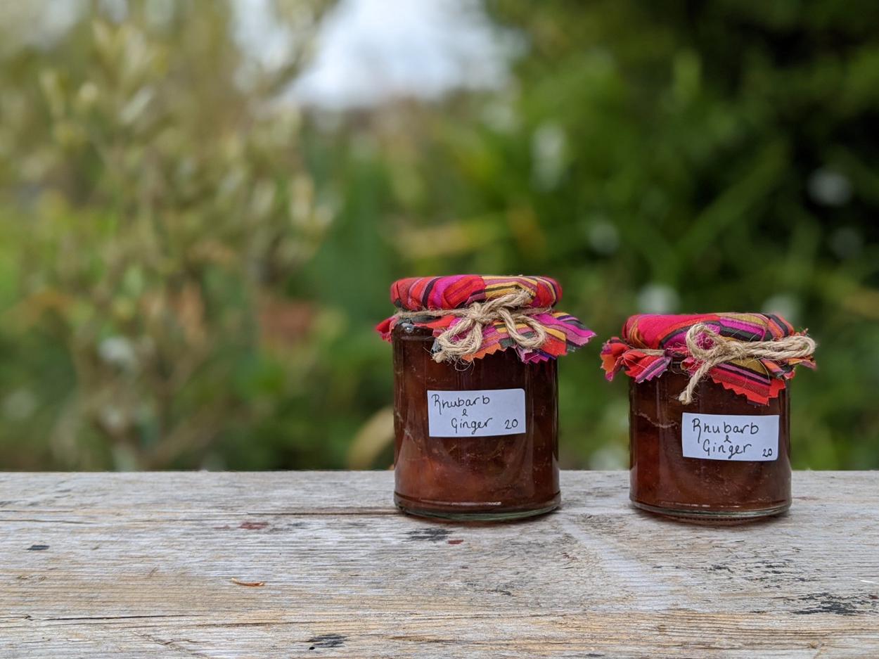 Two jars filled with deep pink jam, cooling outside